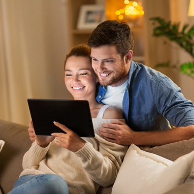 Man and women looking at tablet together smiling in living room