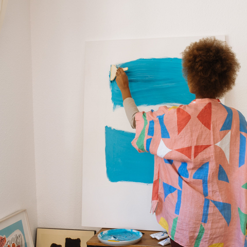 Women painting a canvas with blue paint