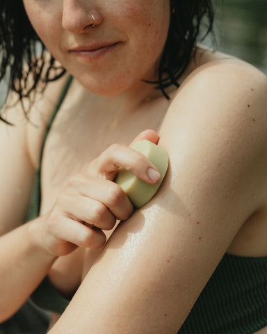 women using bare lotion bar on skin  