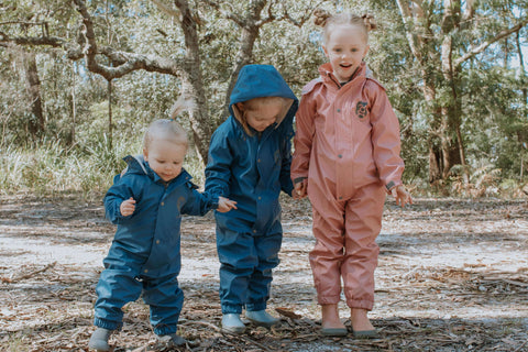 Trio of girls holding hands wearing pink and blue puddle suits