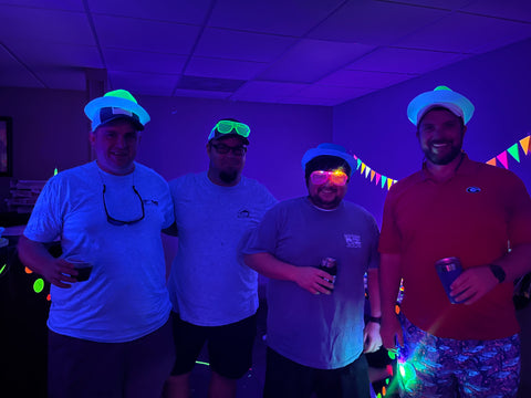 Party guests wearing glow hats and light up sunglasses at glow party