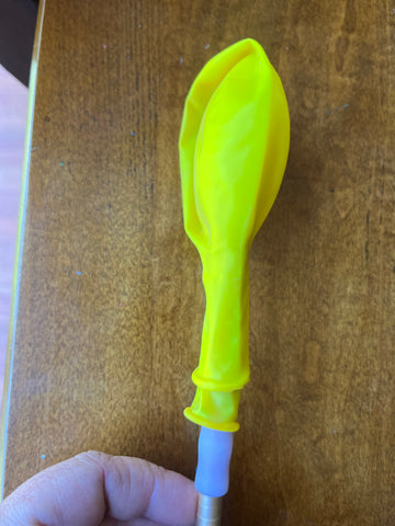 Double stuffed balloon on backside of paint brush. Double stuffing balloons can change the color or make them thicker and less transparent.