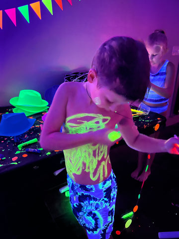 Kid covering themself in glow in the dark body paint