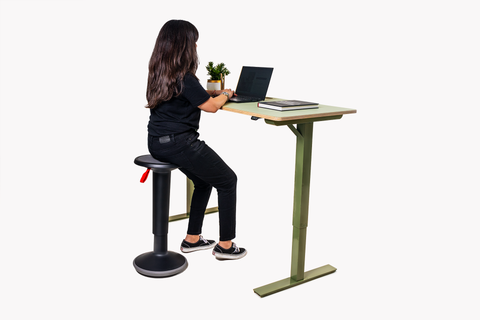 Mujer usando un escritorio de altura ajustable de Euclid Smart Elements, sentada en un taburete UPis1