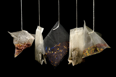Teabags hanging down against a gloomy dark background