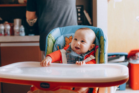 a baby sitting in a baby chair at meal times
