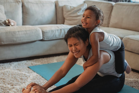A mother attempting to workout with a child climbing on her back