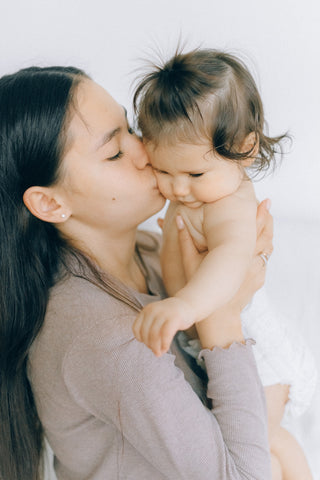 a mother kissing her baby