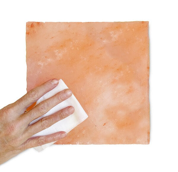 A hand cleaning an himalayan salt block with a dry cloth