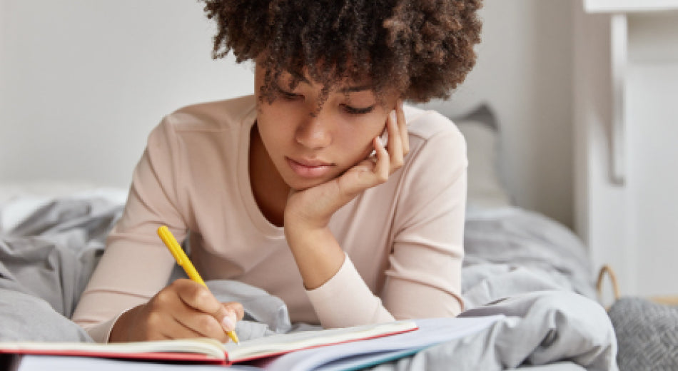 A woman is in bed writing in a journal