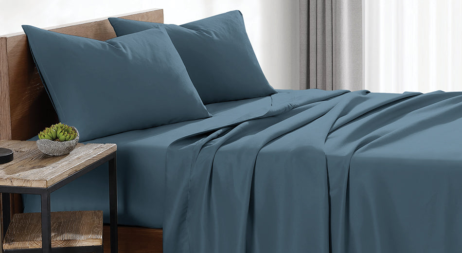 A bed dressed in dark blue sheets is shown from the side.