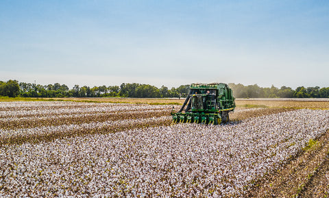 A harvester moves across a plain of farmland