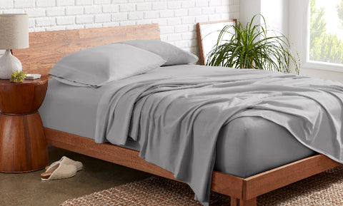 A bed with a grey sheet draped over it in an aesthetic bedroom