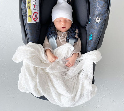 Baby in a car seat with a cellular bamboo baby blanket from Lullalove UK
