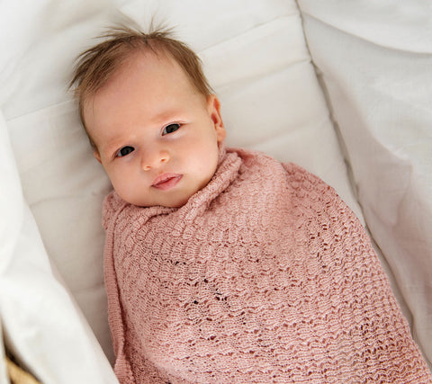 Baby girl swaddled in a pink merino swaddle