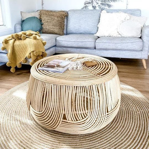 Round coffee table made of rattan with magazines on top