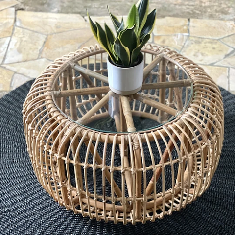A corner view of the Rattan Round Table with a potted plant on top