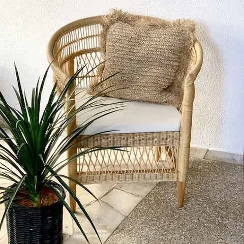 A cushioned Malawi Chair with a rattan pillow on it