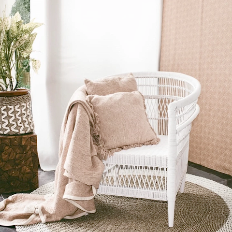 A white chair with pillows and a blanket