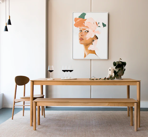 A brown dining table with a painting in the background