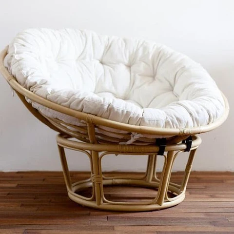 A natural rattan chair with a large white cushioned sea