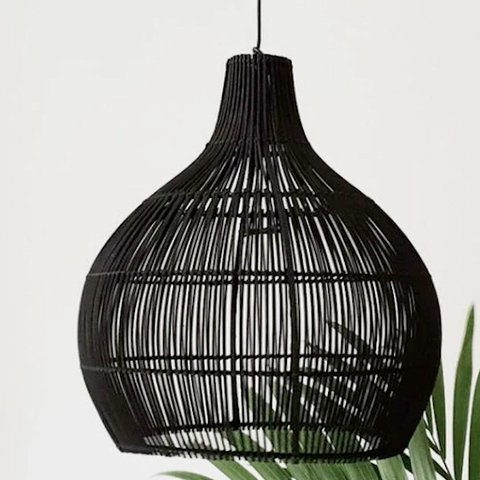 A black rattan lamp with a striped pattern above a plant