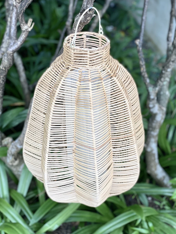 A flower-shaped rattan lamp with a fishbone-like pattern hanging on a tree branch