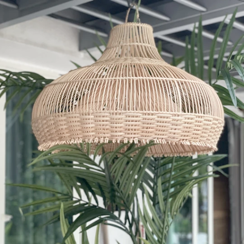 A hanging double layered bell-shaped rattan lamp above outdoor plants