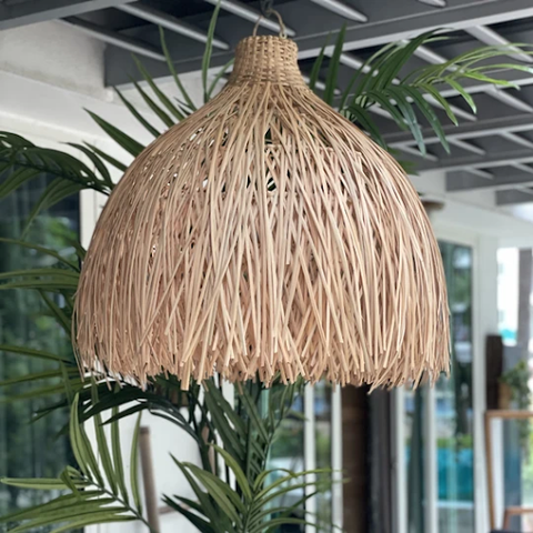 A hanging natural-toned rattan lamp hovering above outdoor plants