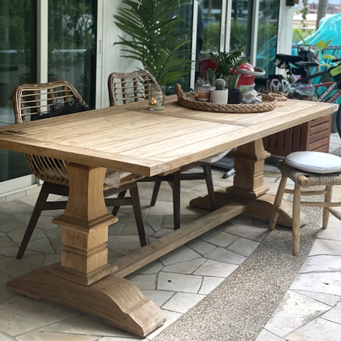 The Rustic Teak Dining Table placed outdoors