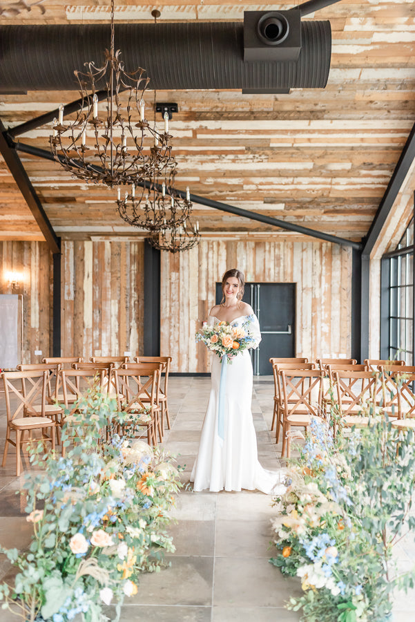 Bride in vintage barn with wedding decorations and chairs
