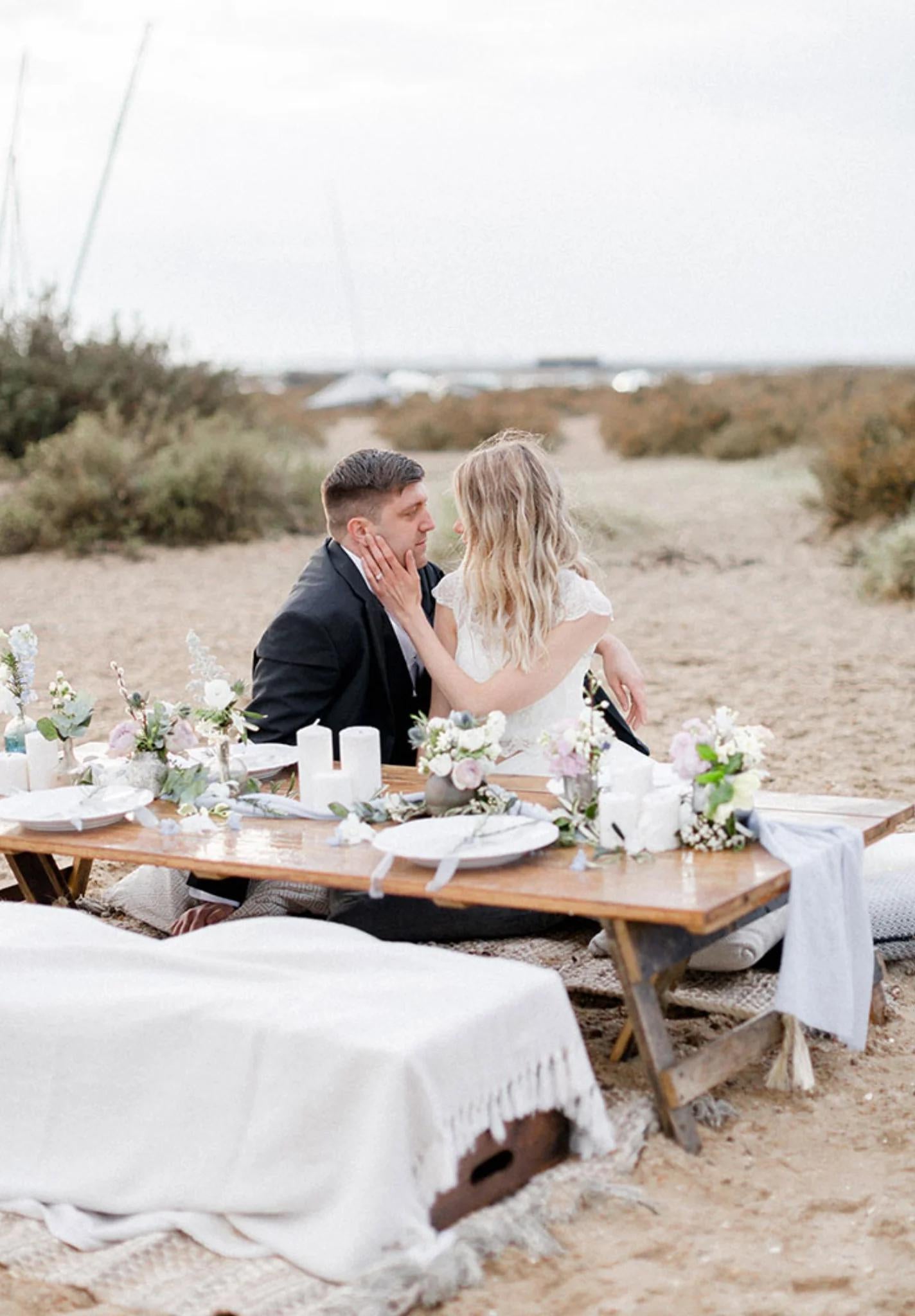 Bride and groom at coastal wedding table on a sandy beach