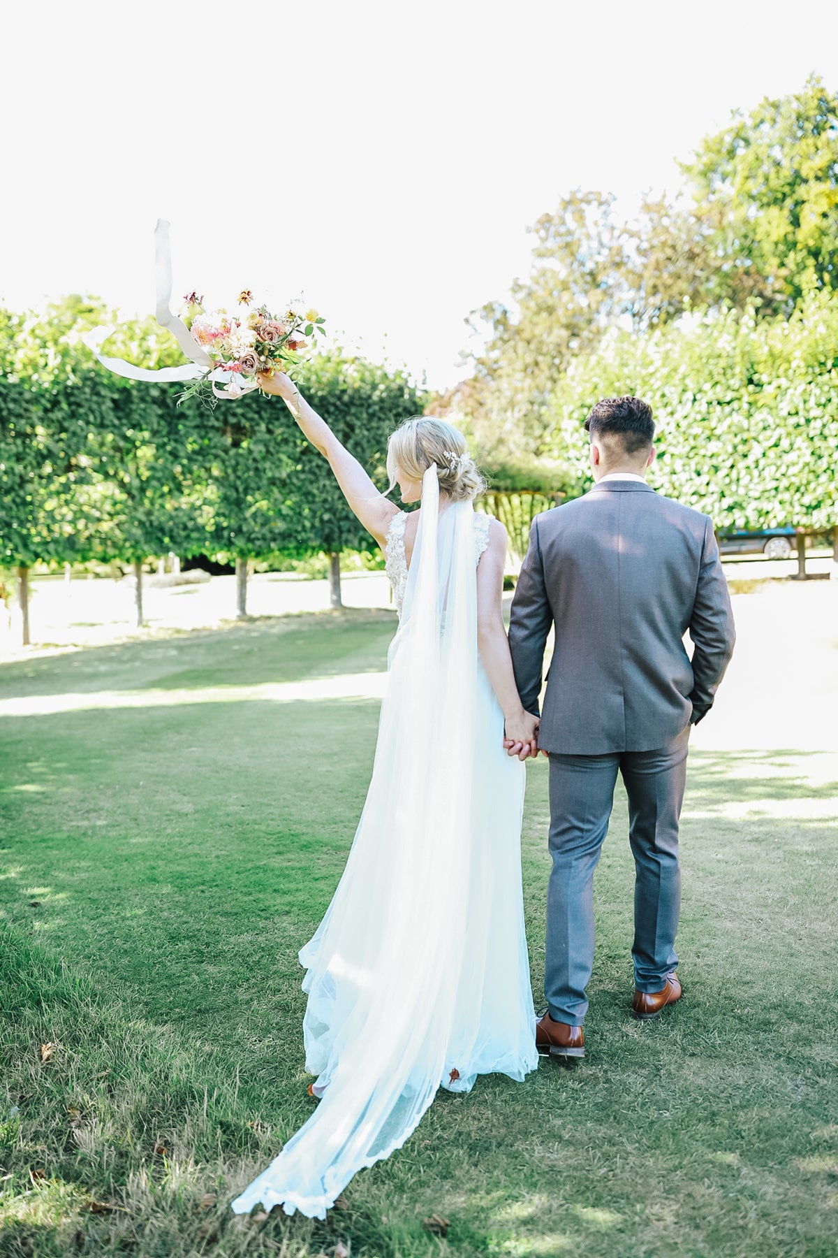 Bride and groom celebrating in park with rows of trees