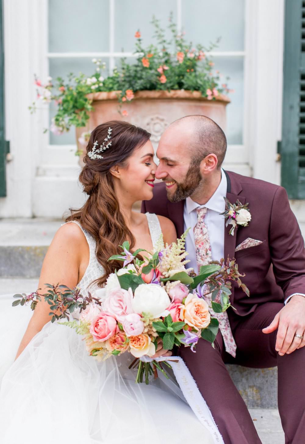Bride and groom kissing and holding pink floral bouquet