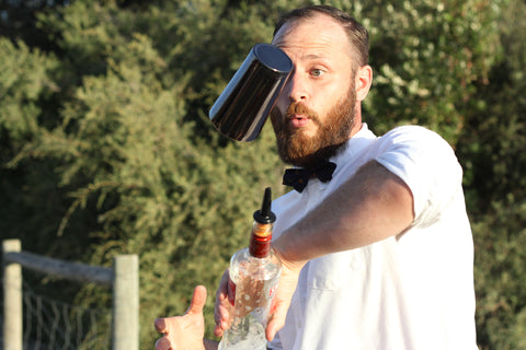 Bartender expertly juggling a liquor bottle with BarFlow speed pourer attached and a Boston Tin shaker