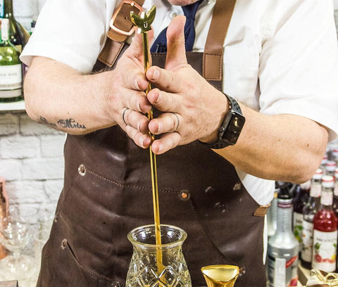 bartender using a swizzle stick to mix a cocktail drink