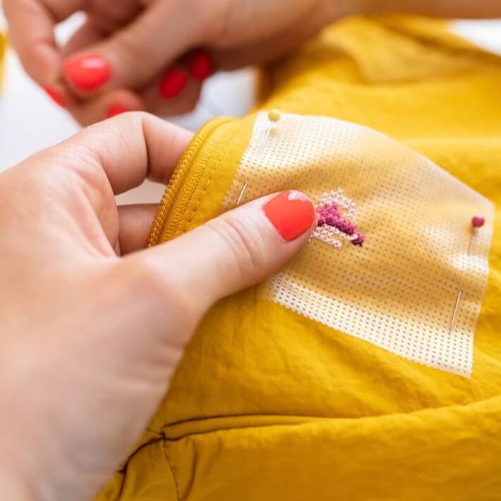 Soluble cross stitch canvas being used to embroider a yellow bag