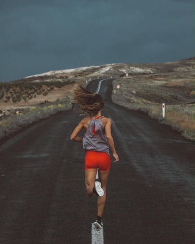 Image of woman running down a long road
