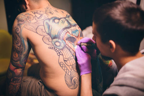 a man having his back tattooed