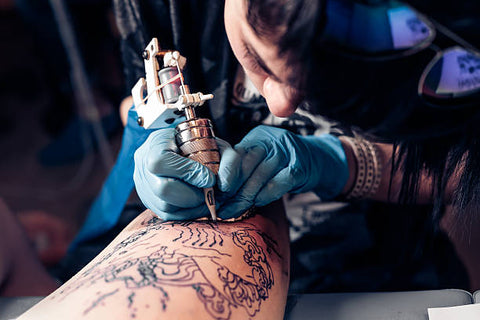 tattoo artist working on client's skin