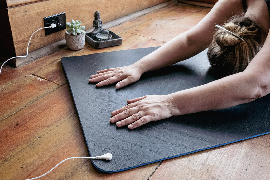 yoga stretching on grounding earthing mat