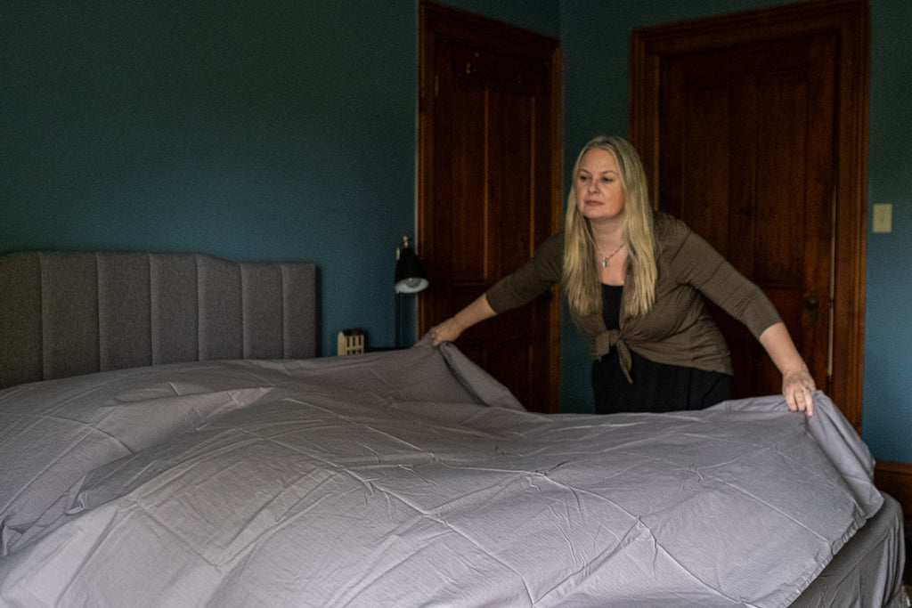 women making a bed with grey sheets