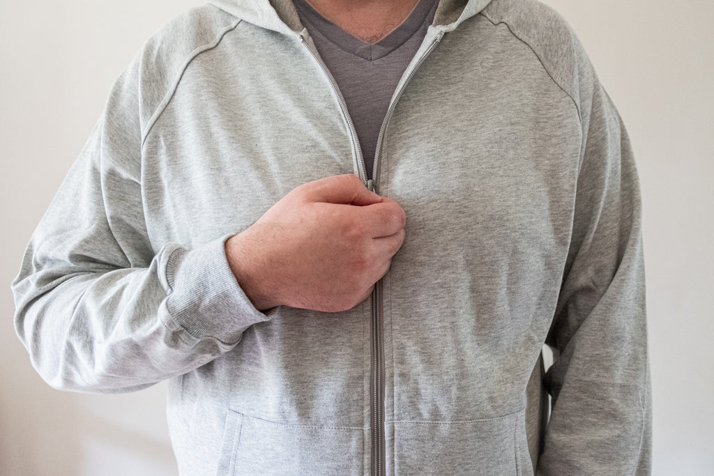 zipping up a grey EMF shielding silver fiber and cotton hoodie sweater