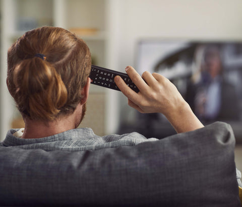 a-man-watching-on-a-sofa-and-watching-a-tv-by-holding-a-tv-remote-control-on-his-right-hand-side