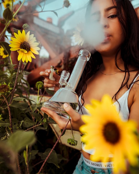 Woman smoking bong next to flowers