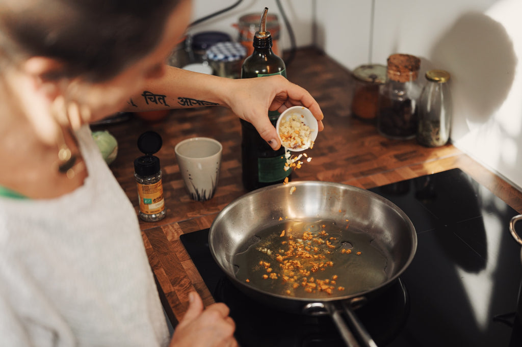 man adding garlic to a pan with oil 