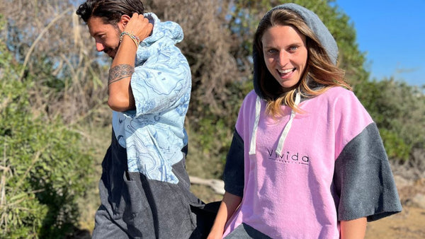 A man and a woman walking in nature wearing Vivida Lifestyle poncho towel changing robes