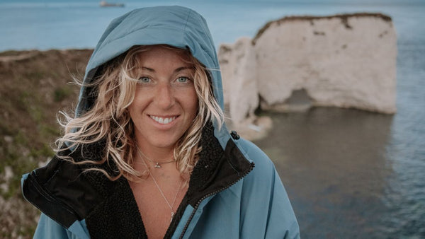 A woman standing on a cliff top wearing a Vivida Lifestyle Waterproof Changing Robe