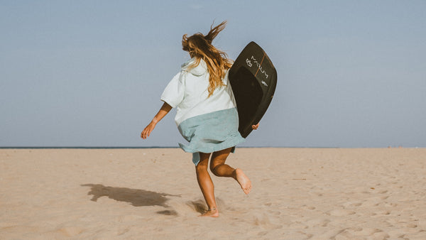 Woman running on a beach in a Vivida Poncho Towel