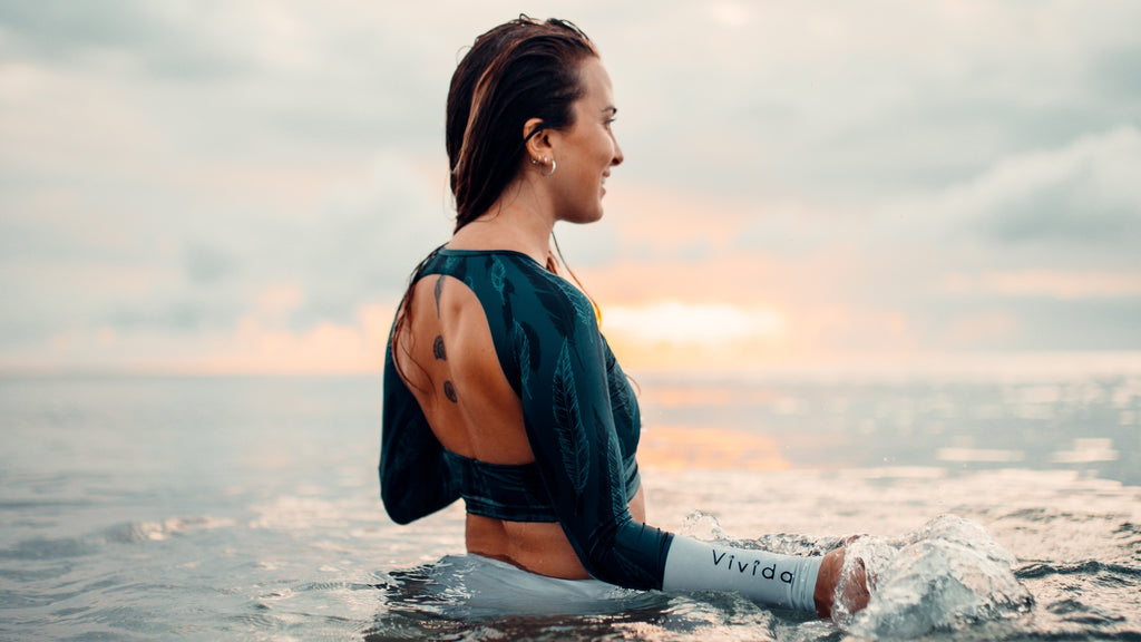 Women standing in the sea wearing a Vivida Women of the Sea rashguard